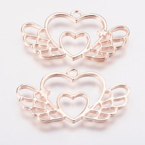 May include: Two gold-tone metal heart-shaped pendant charms with wings. Each charm features a smaller heart inside the larger heart.