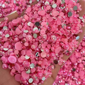 May include: A large assortment of pink and silver embellishments, including pearls, rhinestones, and flat-back gems. These decorative elements are perfect for adding sparkle and dimension to crafts, jewelry, and other projects.