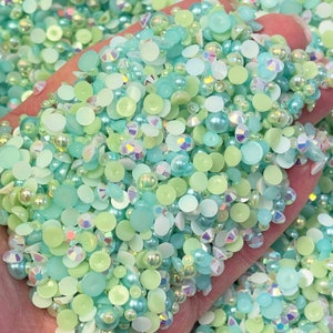 May include: A mix of light blue, green, and white round and flat iridescent beads. The beads are perfect for crafting and jewelry making.