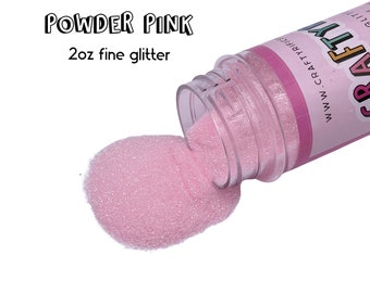 May include: A clear plastic jar with a pink glitter inside. The jar is tipped over and the glitter is spilling out. The jar has a label that says "www.craftytribe.com" and "CRAFT TRIBE". The label also says "Powder Pink" and "2oz fine glitter".