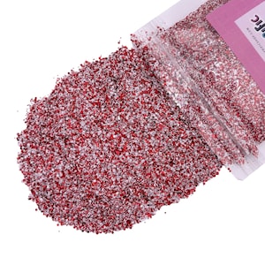 May include: A close-up of a red and silver glitter, spilling out of a clear plastic bag. The bag has a pink label with the text "Twinkle Shop.com" and the word "Chic" in white.