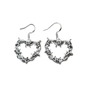 Puede incluir: Un par de pendientes de plata con forma de corazón hechos de alambre de púas.