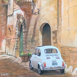 May include: A white vintage Fiat car parked in a narrow, cobbled alleyway in a European city. The car is parked in front of a building with a wrought iron balcony and a green door.