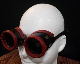 Black and red leather steampunk goggles with darkened lenses.
