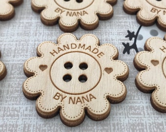 May include: Wooden flower-shaped tags with the text "Handmade by Nana" and a four-hole button design. The tags are light brown and have a distressed look.
