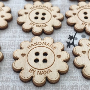 May include: Wooden flower-shaped tags with the text "Handmade by Nana" and a four-hole button design. The tags are light brown and have a distressed look.