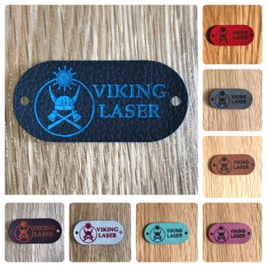 May include: A collection of eight leather labels featuring a Viking helmet and crossed axes design. The labels are available in a range of colours, including red, grey, blue, brown, white, and pink. Each label displays the text "VIKING LASER" printed on it.