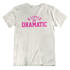 May include: White t-shirt with a pink graphic that says "A Little Bit Dramatic".