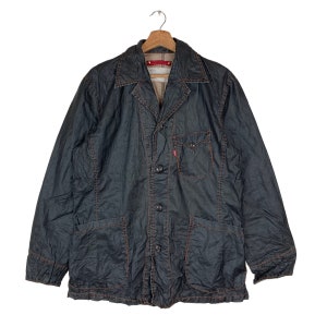 May include: A dark blue denim jacket with a button closure and multiple pockets. The jacket has orange stitching and a red Levi's label on the collar.