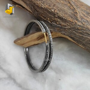 Puede incluir: Un par de pendientes de aro de plata con una fila de peque&ntilde;os diamantes alrededor del borde. Los pendientes est&aacute;n sobre una superficie de madera.