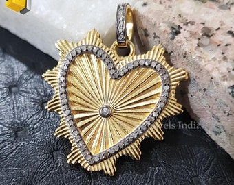 May include: A gold heart-shaped pendant with a diamond-encrusted border. The pendant has a sunburst design in the center and a single diamond in the middle. The pendant is on a white marble background.
