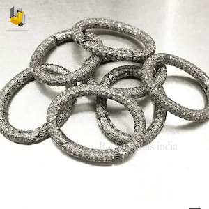 May include: A set of five silver diamond bracelets, each with a delicate, textured design. The bracelets are arranged in a loose pile, showcasing their intricate details.
