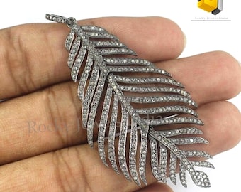 May include: A silver feather pendant with a detailed design of small diamonds. The pendant is a delicate and intricate piece of jewelry.