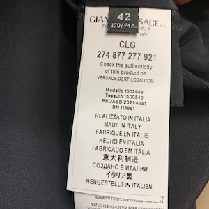 K&ouml;nnte beinhalten: Ein schwarzes Kleidungsst&uuml;cketikett mit wei&szlig;em Text, einschlie&szlig;lich des Markennamens, der Gr&ouml;&szlig;e 42 und eines Produktcodes. Das Etikett enth&auml;lt auch den Text "Made in Italy" und Pflegehinweise.