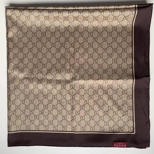 Könnte beinhalten: Ein quadratischer Seidenschal mit einem sich wiederholenden Muster aus ineinandergreifenden "G"-Logos in Braun- und Beigetönen. Der Schal hat einen dunkelbraunen Rand und ein kleines Etikett mit dem Markennamen "Gucci".