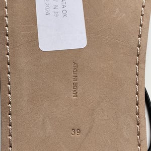 May include: The beige leather sole of a sandal features a white rectangular tag with the text CALZATA OK F1647 N.39 18.12.2024. The sole is embossed with the text MADE IN ITALY and the number 39, with light-coloured stitching along the edges.