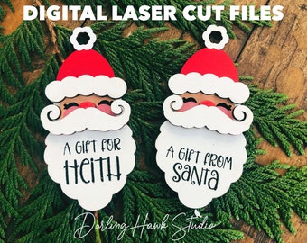 May include: Two white wooden Christmas ornaments shaped like Santa Claus's face. The ornaments have a red hat, white beard, and black eyes. The text "A gift for Heith" and "A gift from Santa" is written on the ornaments.