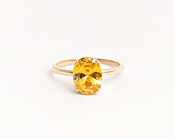 May include: A gold ring with a large, oval-shaped, yellow gemstone.