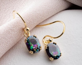 May include: A pair of gold-colored drop earrings. Each earring features an oval-shaped, iridescent gemstone with a spectrum of colors. The gemstones are set in a gold-colored metal with a simple hook design.