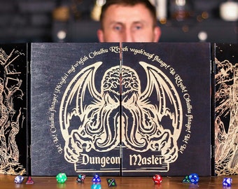 May include: A black wooden Dungeon Master screen with gold-colored engraved artwork. The central panel features a winged creature design, with the text "Dungeon Master" below. Various dice in different colors are scattered on the wooden surface.