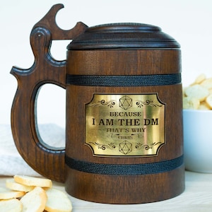 Könnte beinhalten: Ein Bierkrug aus Holz mit einer goldenen Metallplakette, auf der "Because I am the DM That's why (Chris)" steht. Die Plakette hat ein stilisiertes Design mit einem 20-seitigen Würfel.