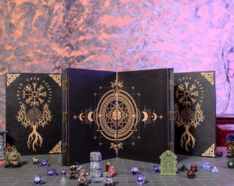 May include: A black four-panel folding screen featuring gold-colored geometric and Norse-inspired designs, including a central star and tree motif. Small painted miniature figures and various multi-sided dice are arranged in front of the screen.