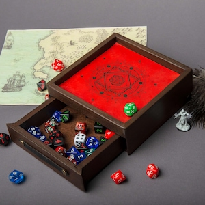 May include: A wooden dice tray with a red interior featuring a black geometric design. The tray's drawer is open, revealing a collection of colorful dice. A map and miniature figure are in the background. The dice are in various colors, including red, blue, and green.