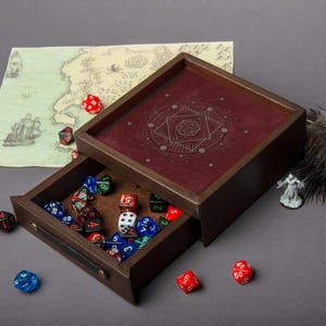 May include: A wooden dice tray with a burgundy interior and geometric design. The tray's drawer is open, revealing a collection of colorful polyhedral dice. A map and miniature figure are also visible.