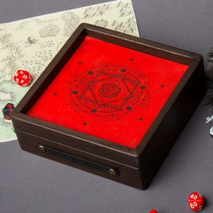 May include: A wooden dice rolling tray with a red felt interior featuring a black geometric design. The tray has a dark brown frame, a black leather handle, and brass-colored hardware. Several dice are scattered around the tray.