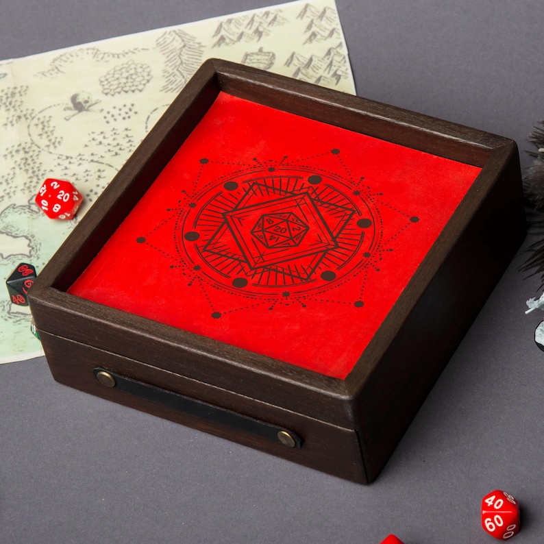 May include: A wooden dice rolling tray with a red felt interior featuring a black geometric design. The tray has a dark brown frame, a black leather handle, and brass-colored hardware. Several dice are scattered around the tray.