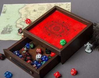 Könnte beinhalten: Eine dunkelbraune Holzwürfelbox mit einer Schublade, die verschiedene mehrseitige Spielwürfel enthält. Die Oberseite ist mit einer leuchtend roten Filzeinlage und einem schwarzen geometrischen Muster versehen. Eine Karte und eine kleine graue Figur liegen daneben.