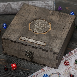 May include: A weathered wooden box, embossed with a dragon emblem and the words "DUNGEONS & DRAGONS". Dice, a pipe, and a map are scattered around, indicating a tabletop role-playing game.