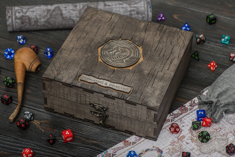 May include: A weathered wooden box, embossed with a dragon emblem and the words "DUNGEONS & DRAGONS". Dice, a pipe, and a map are scattered around, indicating a tabletop role-playing game.