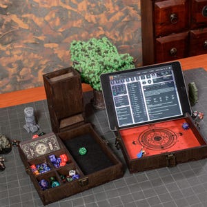 Könnte beinhalten: Ein hölzernes Tabletop-Gaming-Set mit einem Würfelturm, einer Würfelschale und Aufbewahrungsfächern. Das Set enthält ein Tablet, das eine Spieloberfläche anzeigt, Würfel und Spielsteine. Das Set ist dunkelbraun gebeizt und hat einen roten Innenraum.