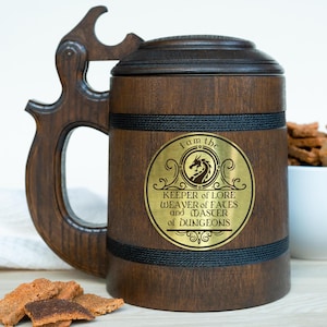Op de afbeelding: Een houten bierkan met een zwarte band en een gouden metalen plaatje met de tekst "Ik ben de Bewaarder van Kennis Wever van Lotgevallen en Meester van Dungeons". Het plaatje heeft een drakenontwerp.