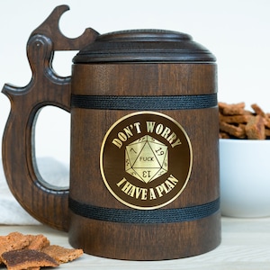 May include: A dark brown wooden beer stein with a lid and a large handle. The stein has a gold emblem with the text "DON'T WORRY FUCK I HAVE A PLAN". A black rope detail wraps around the middle of the stein.