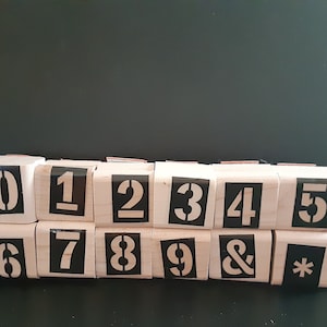 May include: A set of 12 wooden stamps with black ink, featuring the numbers 0-9, an ampersand, and an asterisk.