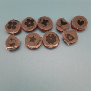 May include: Nine round rubber stamps with various designs, including a flower, a bird, a heart, a star, a cupcake, and a coffee cup. The stamps are all brown and have the text "Stampin' Up!" printed on them.