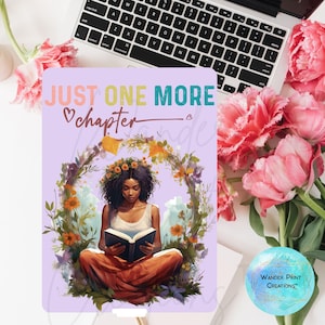 May include: A purple and lavender background with the text "JUST ONE MORE chapter" in colorful letters. A woman with dark skin and long dark hair is sitting in a wreath of flowers and reading a book. The woman is wearing a white shirt and brown pants.