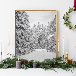 Könnte beinhalten: Ein gerahmtes Schwarz-Weiß-Foto einer schneebedeckten Waldszene. Das Foto wird über einem Kaminsims mit Grün, Kerzen und Ornamenten ausgestellt. Rechts hängt ein grüner Kranz an der Wand.