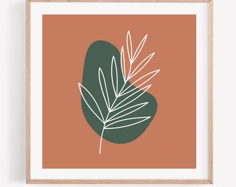 May include: Abstract art print featuring a white line drawing of a leaf over a dark green organic shape, set against a terracotta background. The artwork is framed in a light wood frame, creating a minimalist aesthetic.