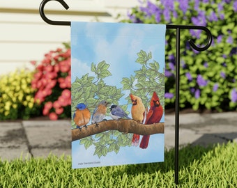 May include: A garden flag with a blue sky background and a branch with five birds. The birds are a bluebird, a cardinal, a chickadee, and two robins. The flag has the text "Julie Townsend Studio" at the bottom.
