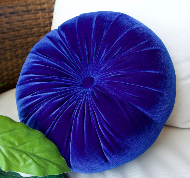May include: A round, blue velvet pillow with a tufted design. The pillow is soft and plush, and would be a great addition to any living room or bedroom.