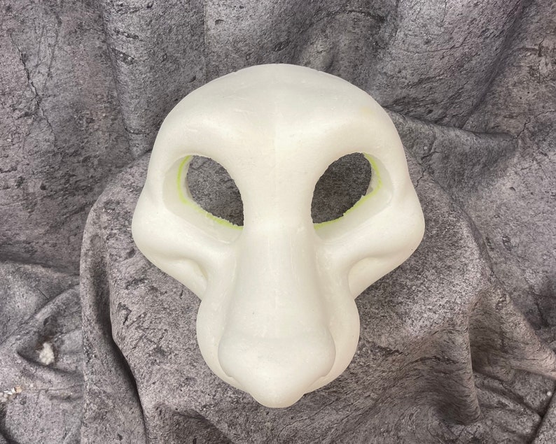 Puede incluir: Cabeza de fursuit en blanco de espuma blanca con aberturas para los ojos y la boca. La cabeza est&aacute; sobre un fondo gris texturizado.