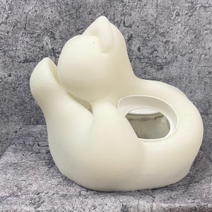 K&ouml;nnte beinhalten: Wei&szlig;er Keramik-Pflanztopf in Form einer zusammengerollten Katze mit einer runden &Ouml;ffnung f&uuml;r eine Pflanze.