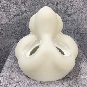 K&ouml;nnte beinhalten: Eine wei&szlig;e, glatte, 3D-gedruckte Maske mit zwei gro&szlig;en L&ouml;chern an den Seiten und einem kleineren Loch in der Mitte. Die Maske ist so konzipiert, dass sie einem Gesicht &auml;hnelt.