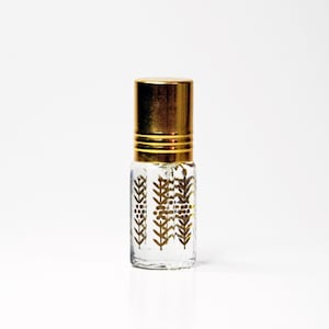 Puede incluir: Pequeña botella de perfume de vidrio transparente con tapa dorada. La botella está decorada con un diseño dorado de hojas y bayas. La botella mide aproximadamente 7,6 cm de altura.