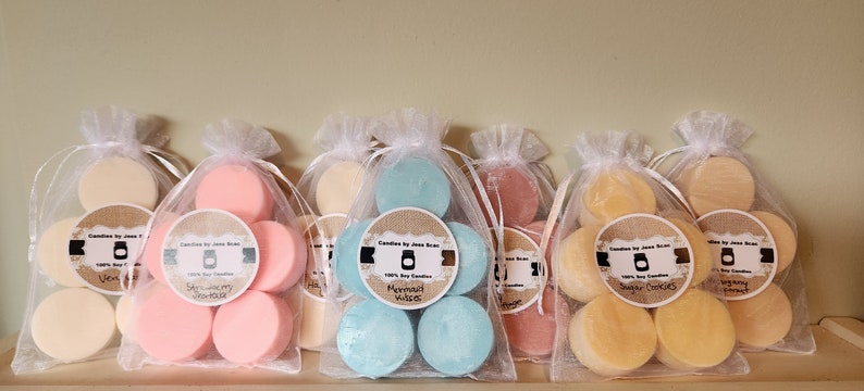 Puede incluir: Varias velas peque&ntilde;as y redondas de cera de soja perfumada en bolsas de organza. Las velas son de varios colores, incluyendo rosa, azul y amarillo. Cada bolsa tiene una etiqueta con el texto "Candles by Jess Bean" y un nombre de aroma.