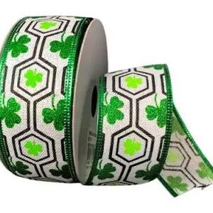 May include: Green and white ribbon with a repeating pattern of shamrocks and black geometric shapes. The ribbon is on a spool.