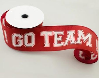 May include: A roll of red ribbon with the words "GO TEAM" printed in white block letters. The ribbon is unspooled, revealing the text and a white spool.